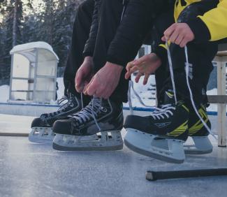 Luistimien nauhojen kiinni laittoa jäällä.