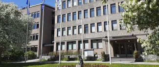 Kaupungintalo edestäpäin kuvattuna, omenapuut kukkivat ja liput liehuvat tangoissa.