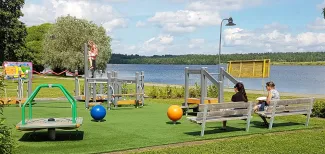 Kaksi naista istuu senioripuistossa Hertunrannassa ja katselee puiston laitteessa kiipeilevää tyttöä..