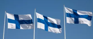 Kolme Suomen lippua liehuu tangossa vierekkäin.