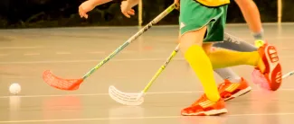 Salibandyä pelaavien ihmisten mailat ja jalat.