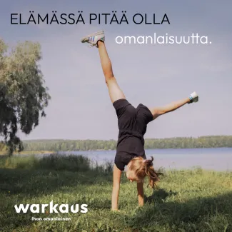 Tyttö seisoo käsillään nurmikolla Hertunrannassa.