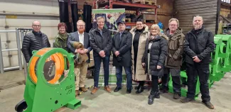 Ryhmäkuva, jossa Lehtoniemen Metallin ja Varkauden kaupunginhallituksen elinvoimajaoston edustajia seisoo hallitilassa metalliteollisuuden laitteidn edessä. Kuvassa on yhdeksän henkilöä, ja etualalla näkyy vihreä teollisuuslaite.