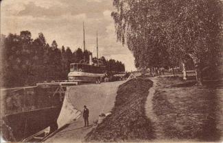 Vanha postikortti Taipaleen kanavalta ruskeasävyinen kuva jossa näkyy Taipaleen kanavan sulku ja yksi ihminen seisomassa kanavan laidalla
