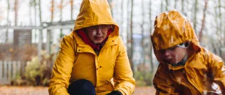 Sadeasuissa olevat aikuinen ja lapsi leikkii päiväkodin pihalla.